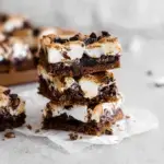 A stack of gooey S'mores Cookie Bars with toasted marshmallows and melted chocolate layers.