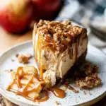 A slice of Salted Caramel Vegan Apple Crumble Cheesecake with caramel drizzle on a plate