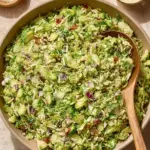A large bowl of Shaved Brussels Sprout Salad topped with grated cheese and walnuts