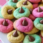 A batch of Spring Blossom Cookies coated in pink and blue sugar with chocolate kisses on top.