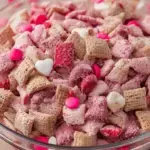 A large bowl of pink Strawberry Chex Mix topped with freeze-dried strawberry slices