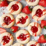 A tray of golden Strawberry Thumbprint Cookies with bright red jam centers on a wire cooling rack