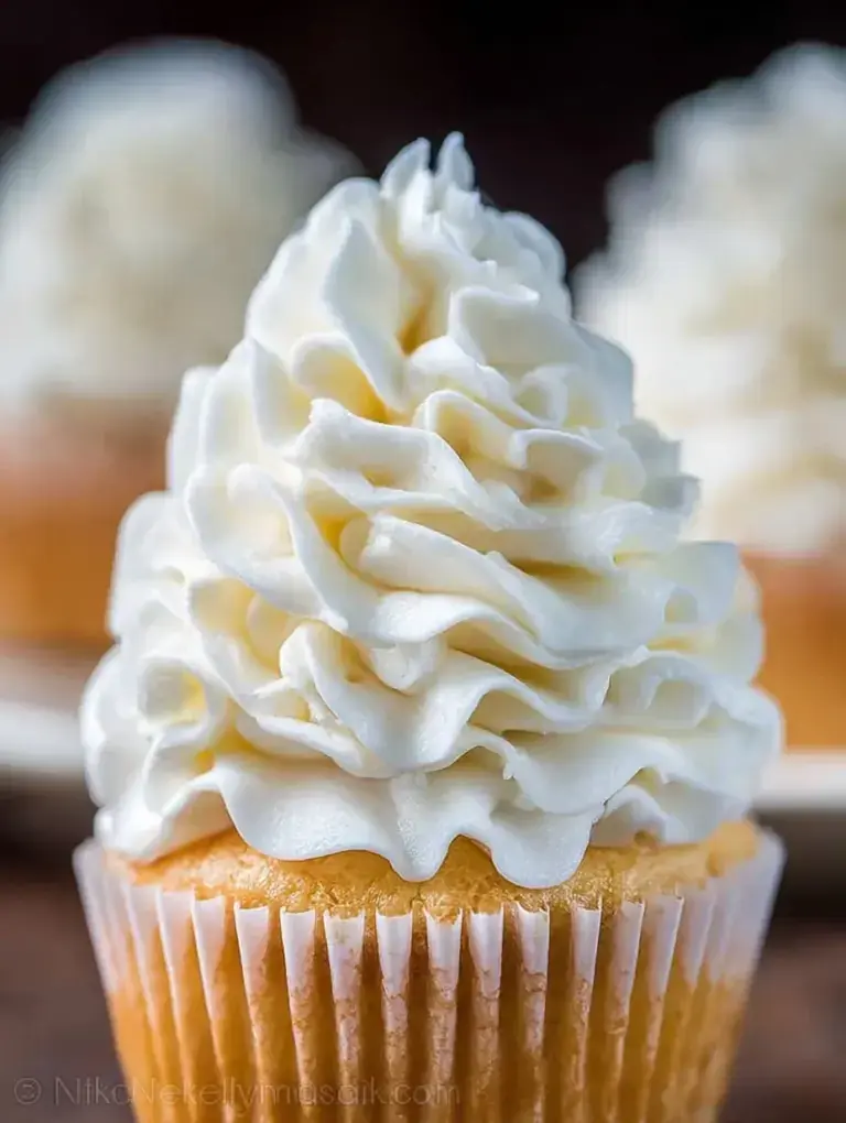 A bowl of fluffy Vanilla Buttercream Frosting with a spatula.