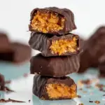 Homemade Vegan Butterfingers stacked on parchment paper showing the flaky peanut butter center