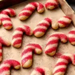 A tray of red and white twisted Vegan Candy Cane Cookies on a cooling rack.
