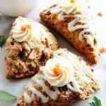 A plate of golden Vegan Carrot Cake Scones drizzled with maple glaze and topped with walnuts