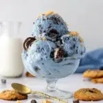 A scoop of vibrant blue Vegan Cookie Monster Ice Cream filled with chocolate chip and sandwich cookie chunks.