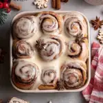 A tray of freshly baked Vegan Gingerbread Cinnamon Rolls drizzled with white vanilla glaze