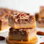A close-up shot of sliced Vegan Pecan Pie Bars on a wooden serving board.