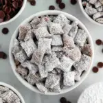 A bowl of powdered sugar coated Vegan Puppy Chow on a wooden table