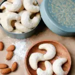 A plate of dusted Vegan Vanillekipferl Crescent Cookies on a festive holiday table