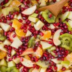 A glass bowl filled with colorful Winter Fruit Salad featuring kiwi, pomegranate, and citrus
