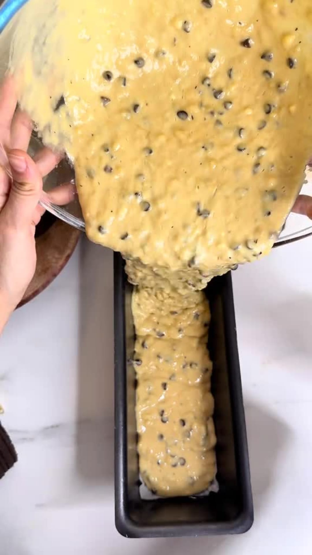 Moist Chocolate Chip Banana Bread - Pouring batter into loaf pan and topping with chocolate chips
